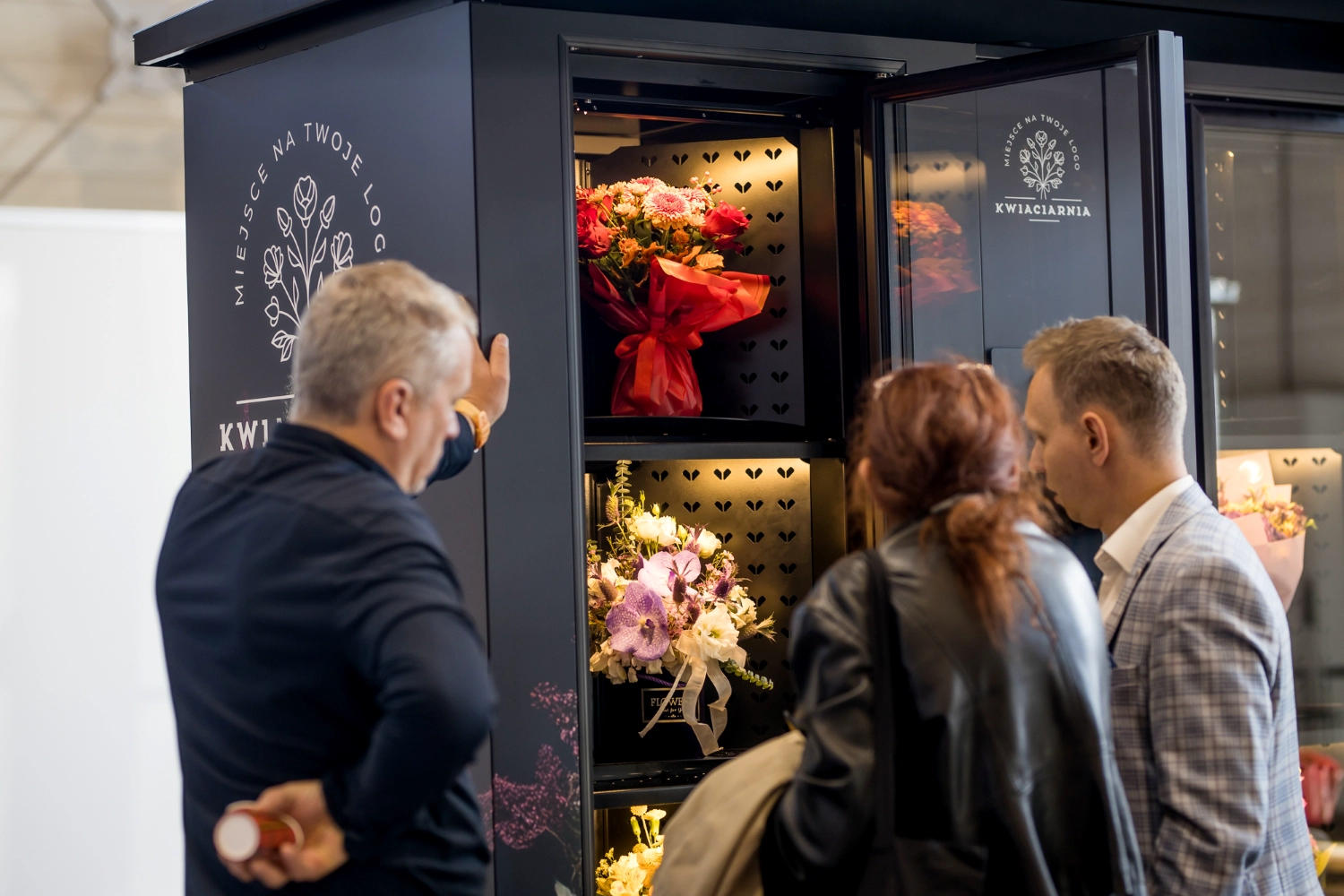 Customers choosing bouquets from a BouquetMat flower vending machine operated by a local florist